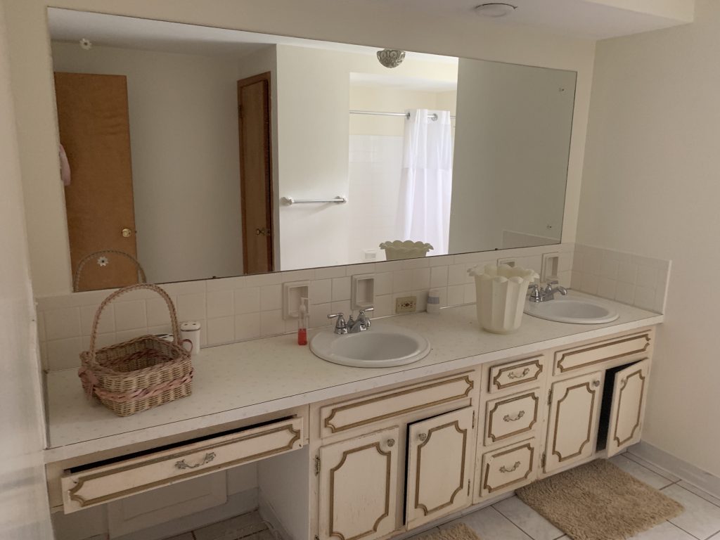 A bathroom with a rectangular mirror the length of the counter.