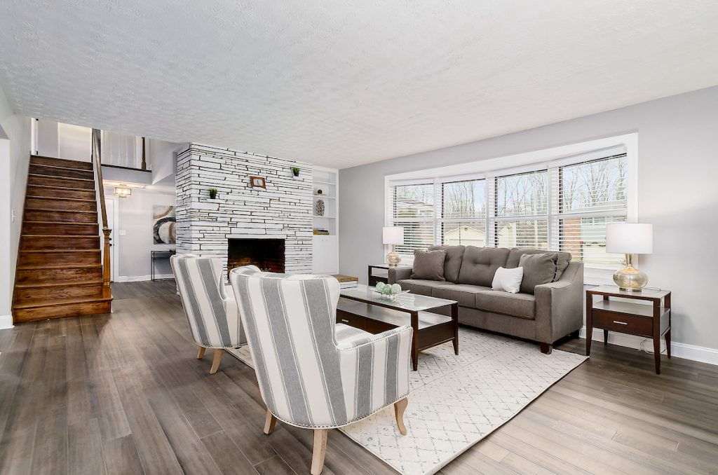 A lovely living room with luxurious chairs, a staircase, and a white rug.