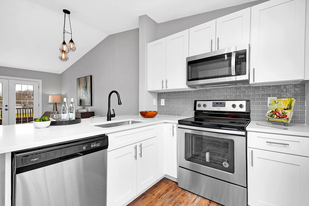 A beautiful kitchen with all white cabinets and updated light fixtures.