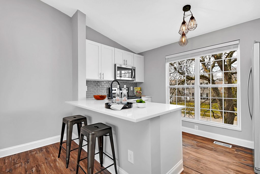 A kitchen with grey tile and stainless steel appliances.