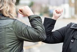 An elbow bump from two people in suits.