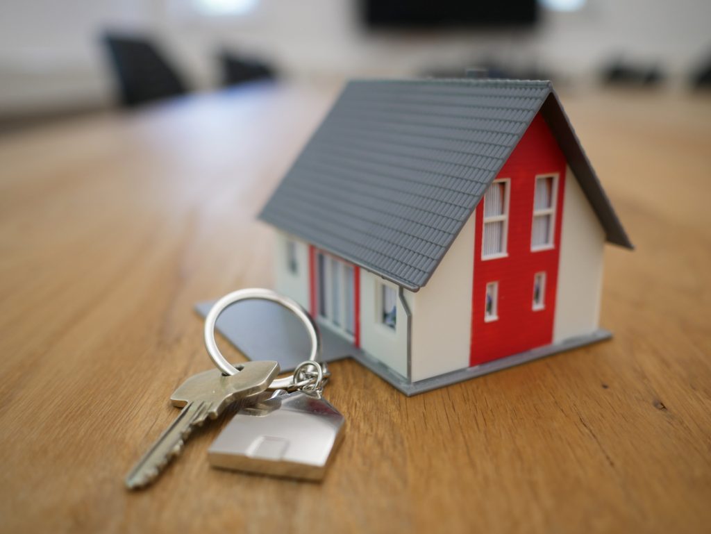 Miniature house with a set of keys on a wooden table.