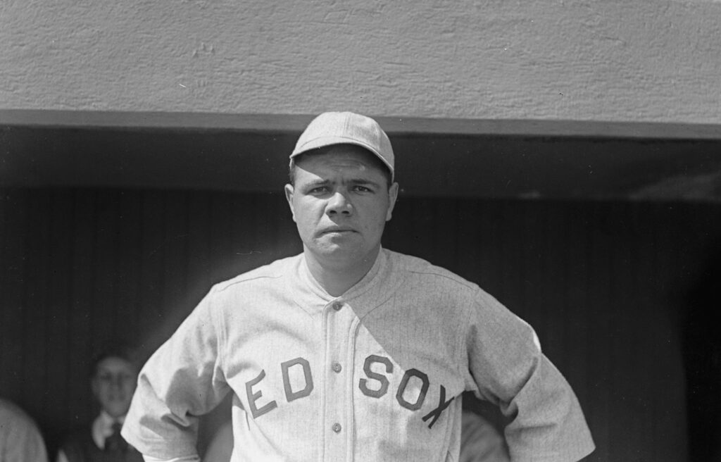 Babe Ruth in his Red Sox jersey with his hands on his hips.