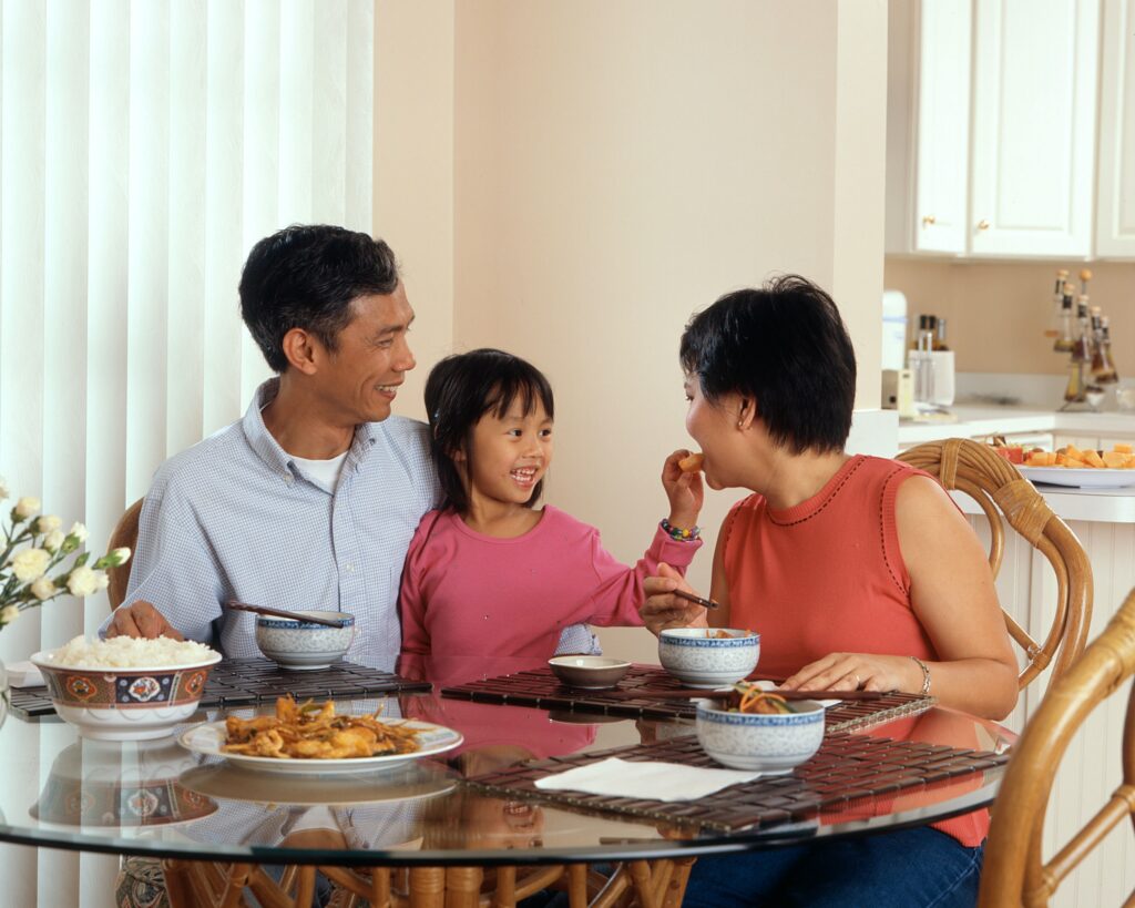 A family of three smiling at the breakfast table in a beautiful home.