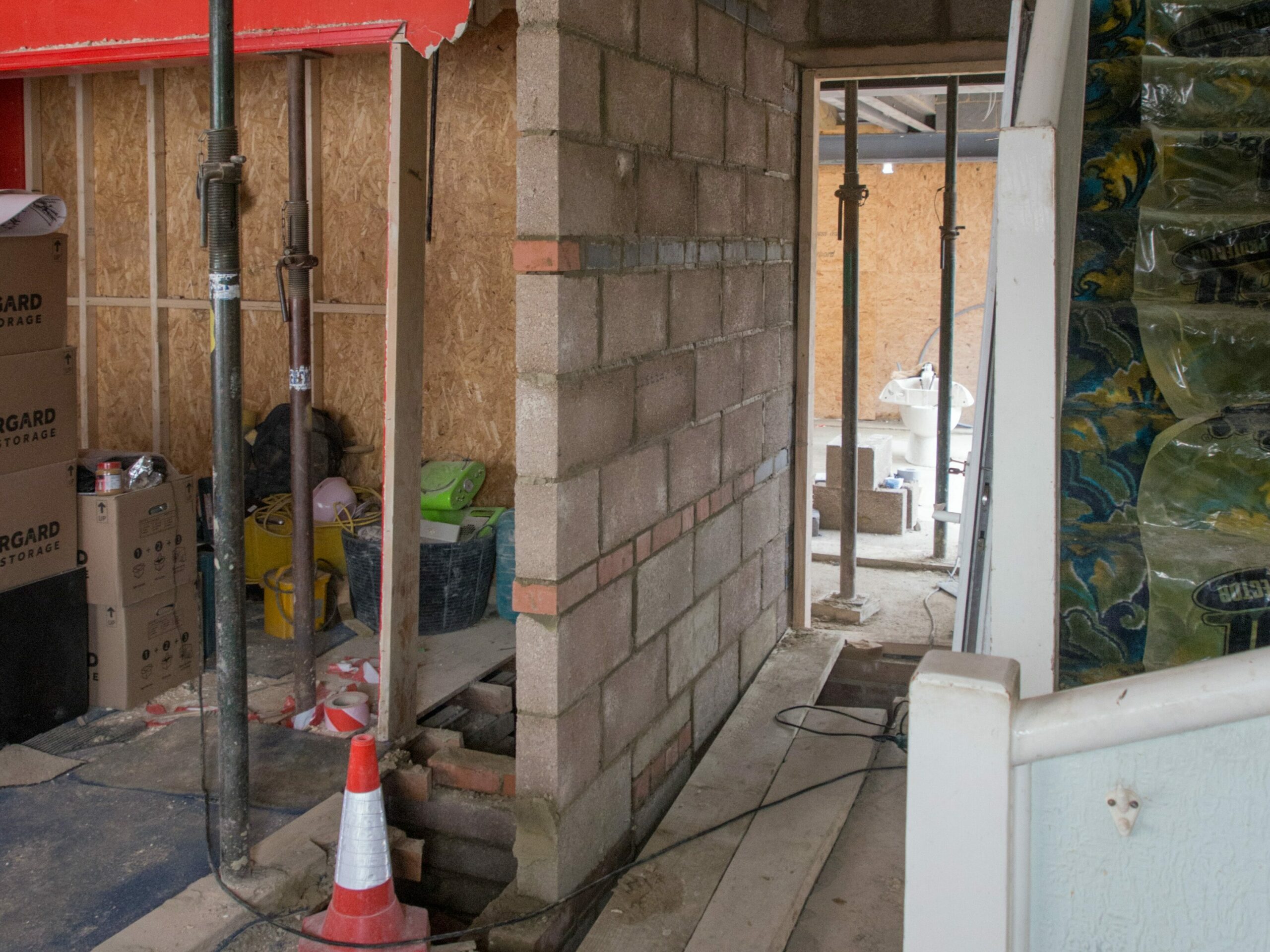 A torn up home in the middle of a renovation project with a traffic come and exposed brick.