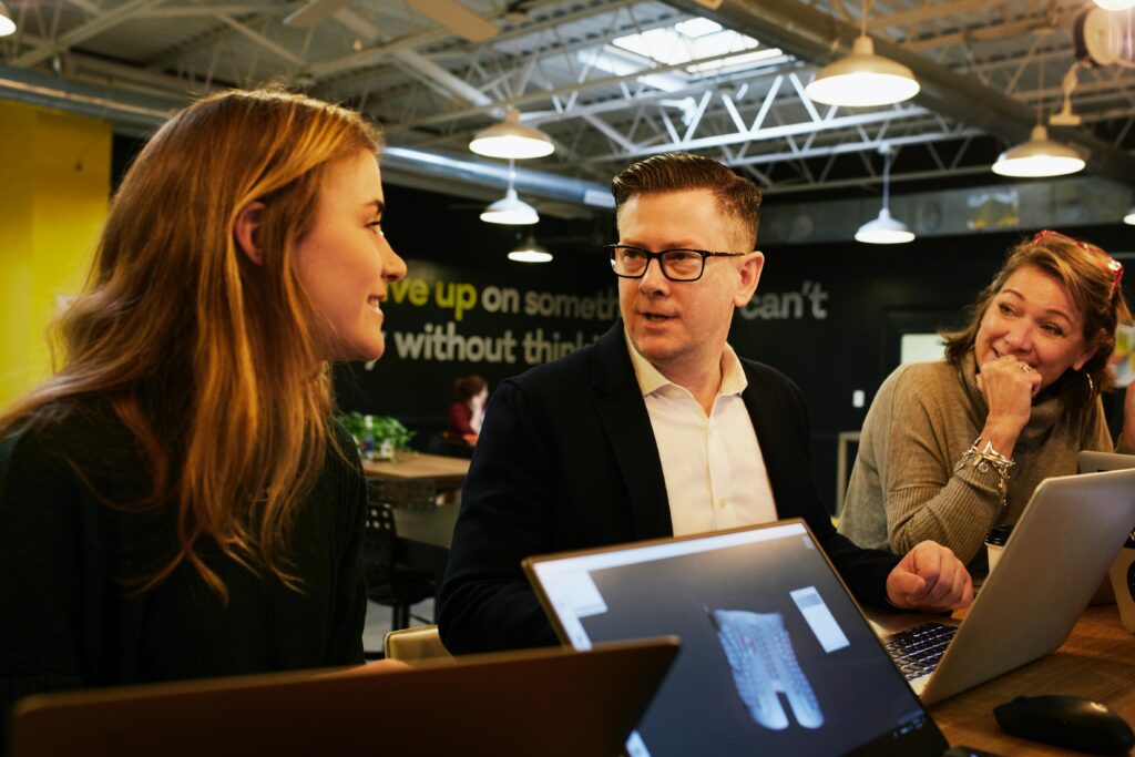 A female real estate investor speaking to a man and a woman at a table. 