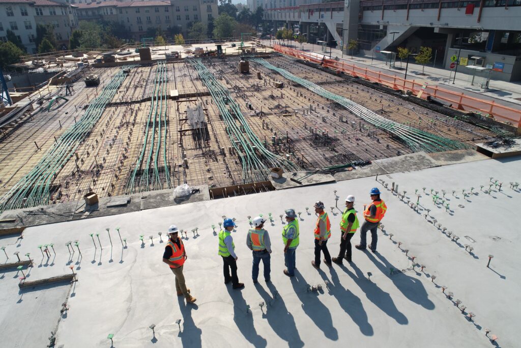 Seven construction workers standing on the roof of a building being built.