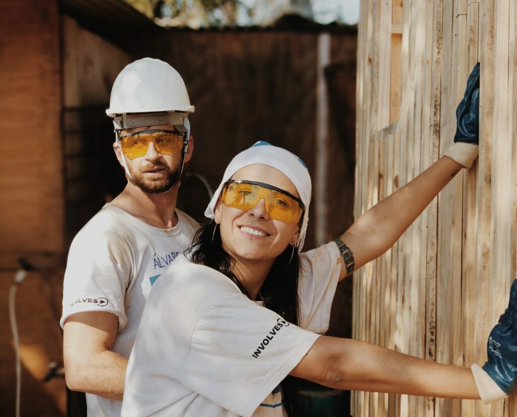 A man and a woman in hard hats working outside on a home renovation project.