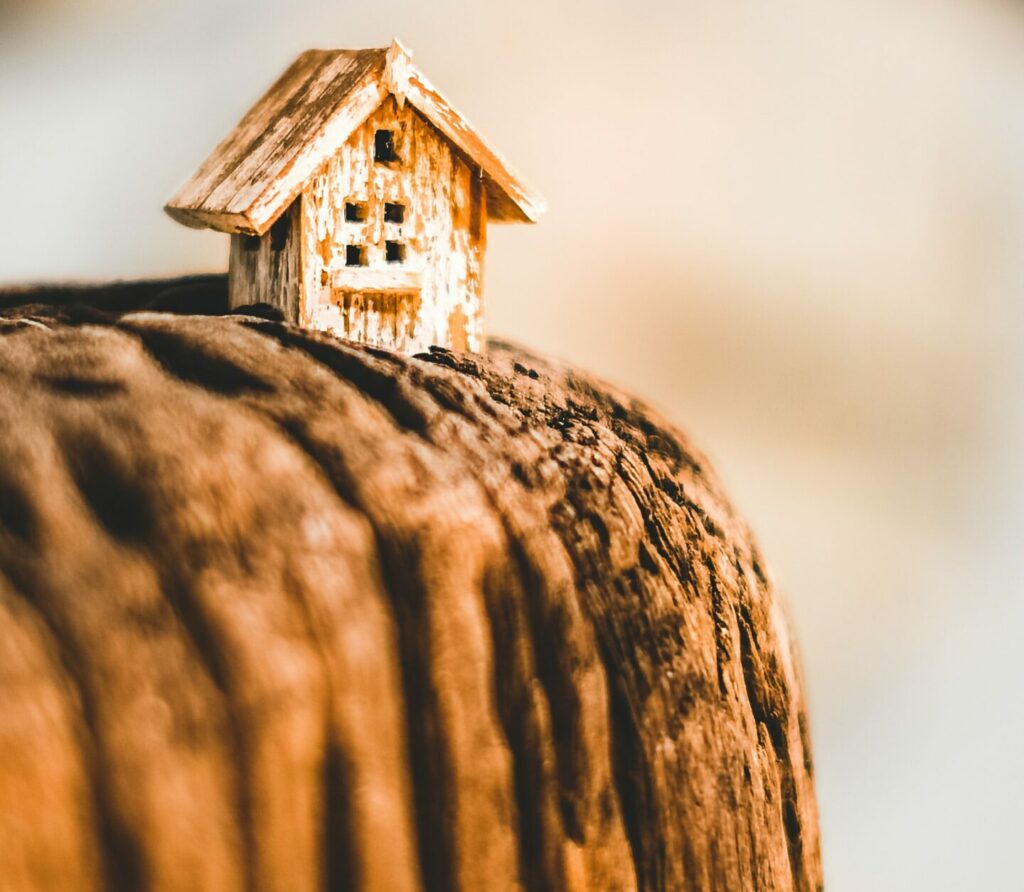 A small model house built on the edge of a large cliff's drop.