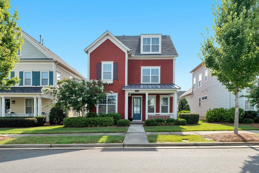 A red three-story house with a mowed lawn.