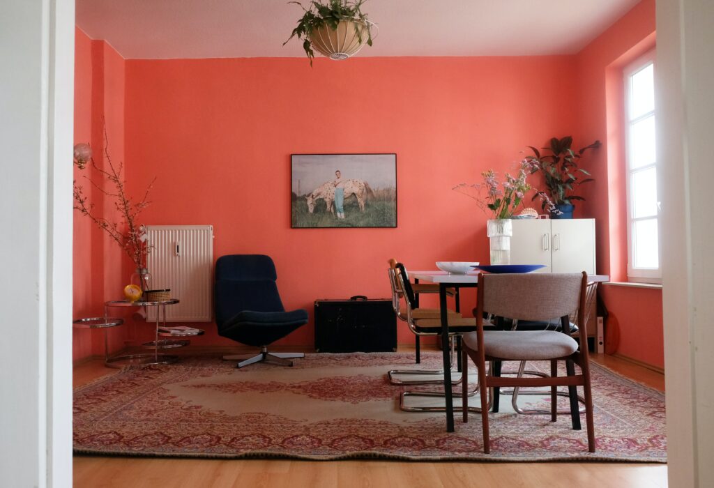 A salmon pink room with a table and chairs