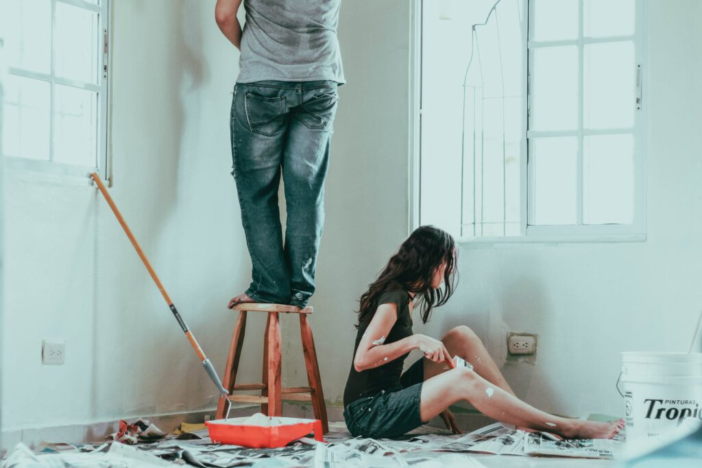 A woman and man painting the interior of a house.