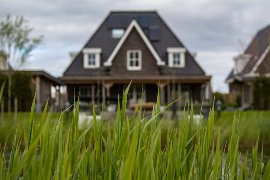 A symmetrical, brown home with tall grass out front.