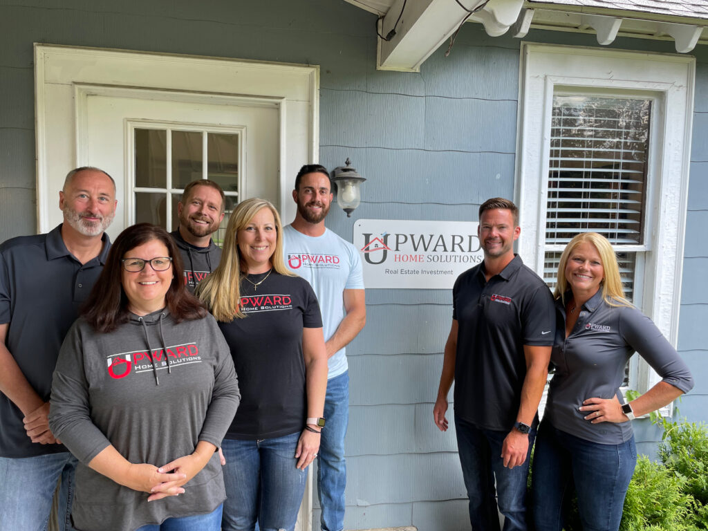 Three female and four male team members at Upward Home Solutions standing in front of their place of business.