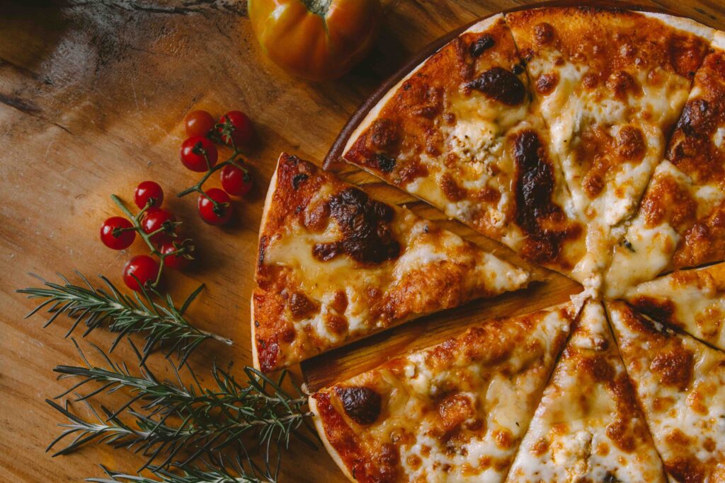 Cheese pizza on a counter in a messy kitchen.