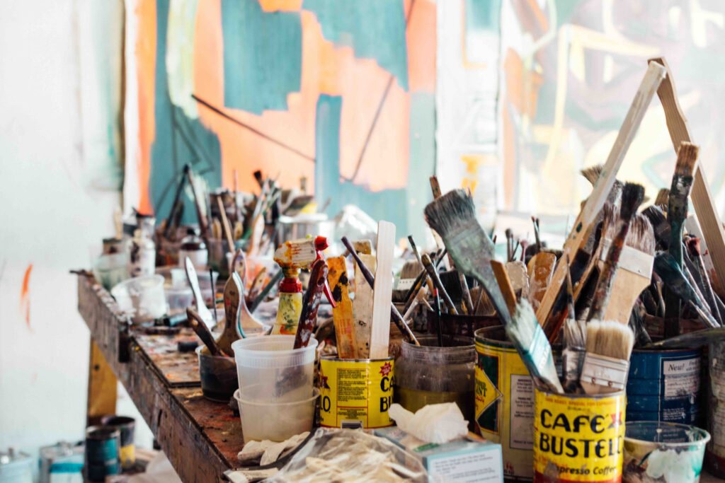 A bunch of art supplies including paintbrushes in an art studio.