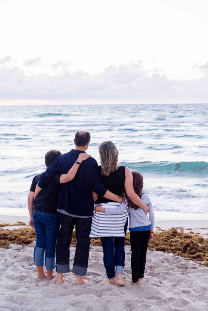 A family hugging on the beach.